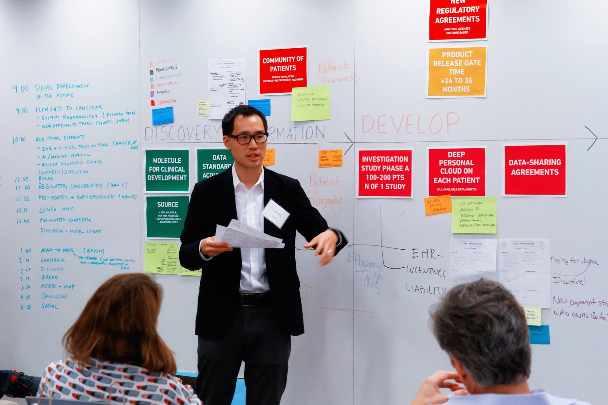 Industry workshop participant speaking during the drug development symposium at the MIT Media Lab, with a whiteboard behind them.